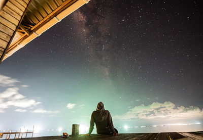 Rear view of man standing against sky at night