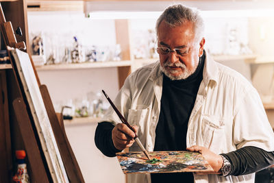 Senior man painting on easel