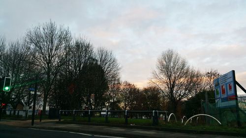Bare trees against cloudy sky