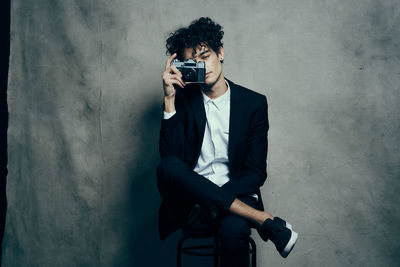 Young man photographing against wall