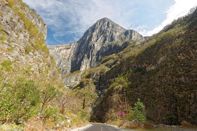 Road passing through mountains against cloudy sky