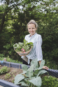 Portrait of a smiling young woman holding plants