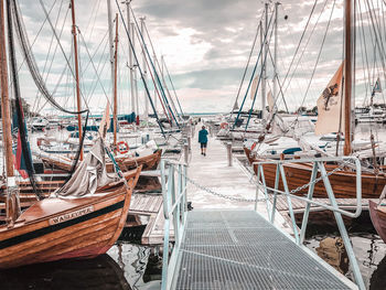 Sailboats moored at harbor against sky