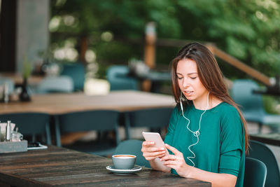 Woman using phone while sitting on table