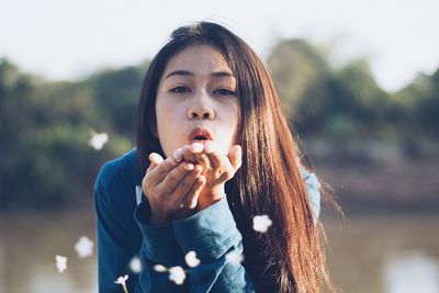 Portrait of young woman blowing flowers