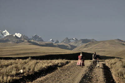 Rear view of people walking on land against sky