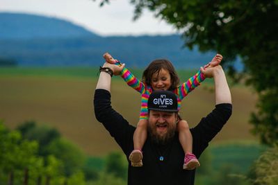 Portrait of happy friends standing against trees against sky