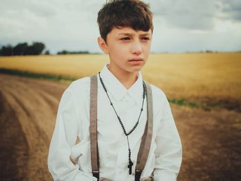 Boy looking away while standing on field