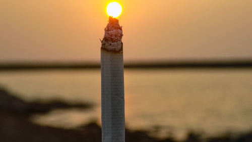 Close-up of illuminated light on beach against sky at sunset