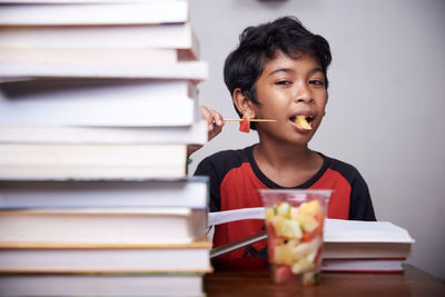 Portrait of boy sitting on stack of books