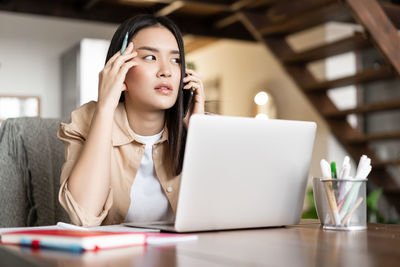 Young woman using mobile phone while sitting at home