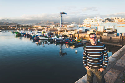 Portrait of smiling man standing against harbor