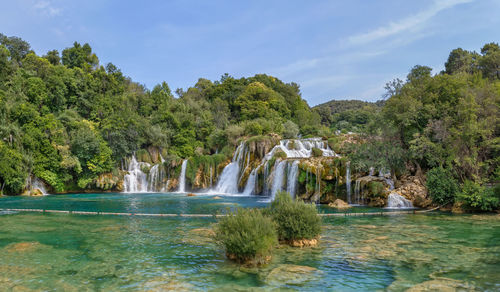 Scenic view of waterfall in forest against sky