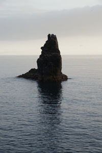 Rock formation in sea against sky