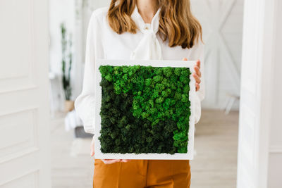 Midsection of woman standing against white wall