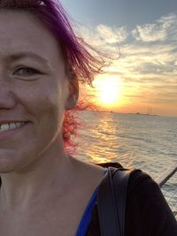 Portrait of smiling young woman against sea during sunset