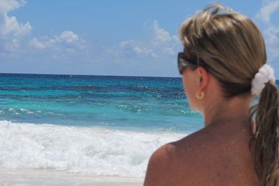 Rear view of shirtless man looking at sea against sky