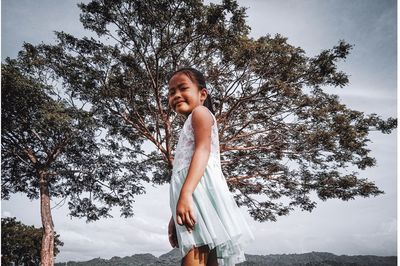 Smiling girl standing against trees