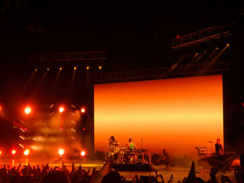 People at illuminated city against sky at night