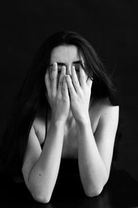 Portrait of young woman against black background