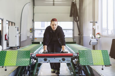 Female mechanic operating hydraulic lift in auto repair shop