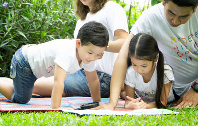 Children with parents looking at drawing in park
