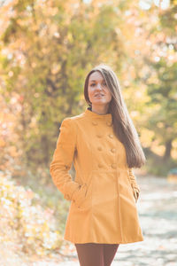 Portrait of a smiling young woman standing against trees