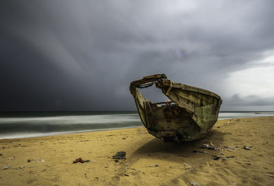 Abandoned boat on beach against sky