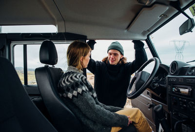 Smiling man and woman talking while sitting in car