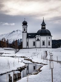 Church by snow covered building against sky