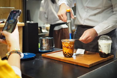 Midsection of man preparing boba tea on table