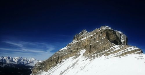 Low angle view of snowcapped mountain against blue sky