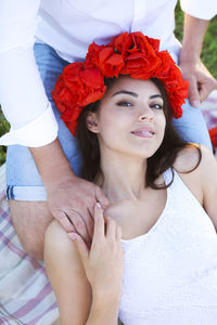 Portrait of smiling woman wearing flowers lying on man lap