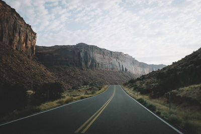 Empty road along rocky mountains