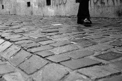 Low section of man walking on cobblestone