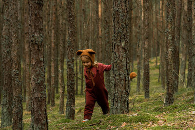 Full length of man standing by tree trunk in forest