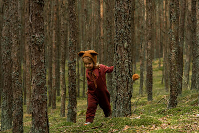 Toddler baby girl in bear bonnet walking in the woods