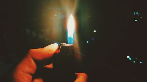 Close-up of hand holding lit candle