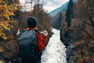 Rear view of man looking at waterfall during winter