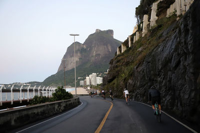 People on road by mountain against sky