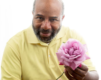 Portrait of man with pink flowers against white background