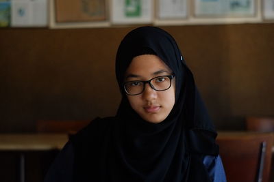 Portrait of girl wearing hijab and eyeglasses at restaurant