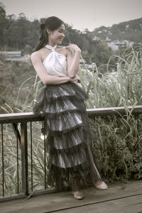 Side view of young woman standing by railing