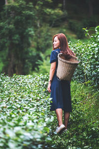 Young woman standing against plants