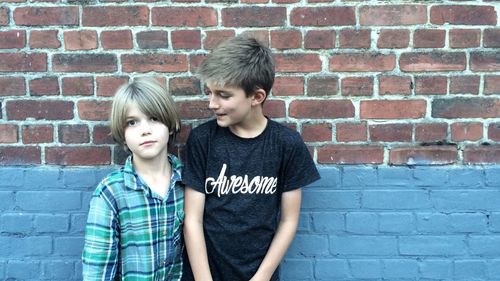 Brother looking at boy while standing against wall