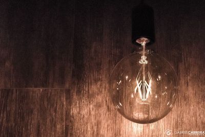 Close-up of light bulb hanging on wood