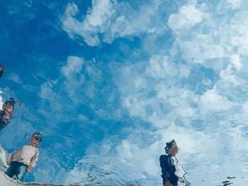 Low angle view of men standing against blue sky