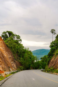 Road by trees and sea against sky