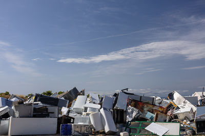 A vast heap of discarded appliances, furniture, and metal clutter lies in an open junkyard.