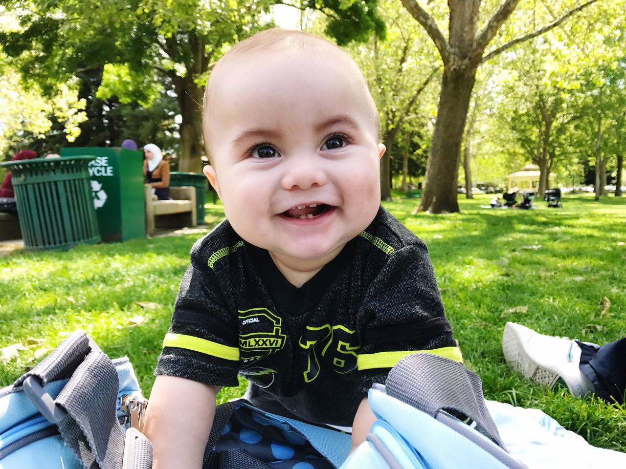 baby, portrait, happiness, cute, looking at camera, smiling, toddler, fun, innocence, park - man made space, leisure activity, childhood, sitting, cheerful, babies only, real people, one person, people, day, outdoors, nature, human body part, adult